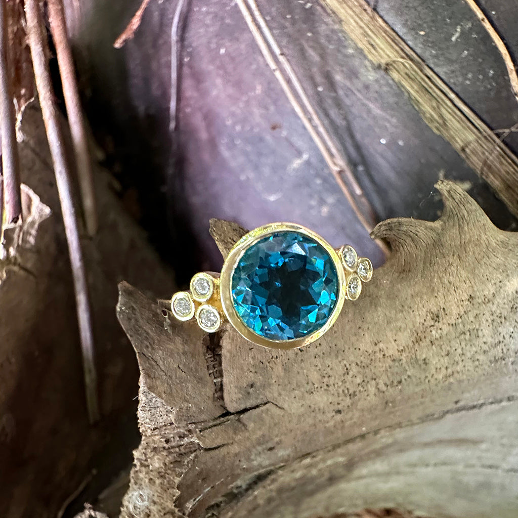 Delicately Bezel Set Blue Topaz with Trilogy Shoulder Diamond Highlight Yellow Gold Ring