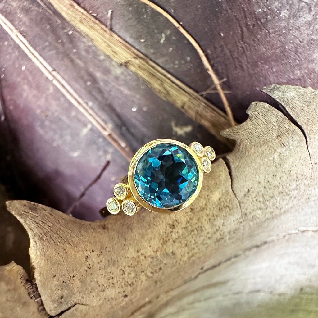 Delicately Bezel Set Blue Topaz with Trilogy Shoulder Diamond Highlight Yellow Gold Ring