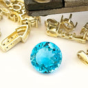 Gold jewelry components and a blue gemstone on a white background