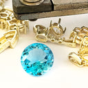 Blue gemstone with gold jewelry components on a white background