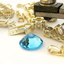 Gold jewelry components with a blue gemstone on a white background