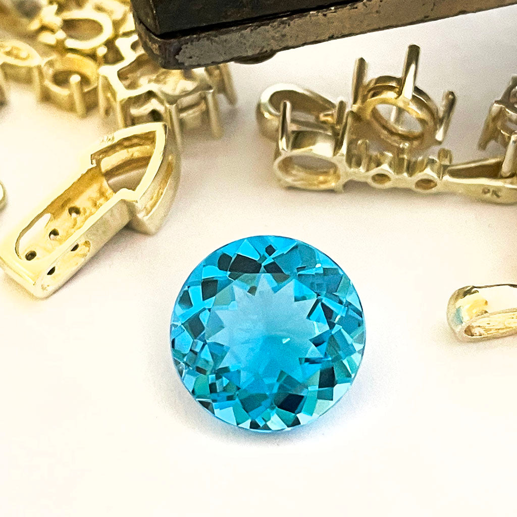 Blue gemstone with gold earring components on a white background
