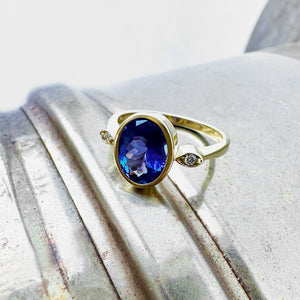 Elegant Oval Bezel Set Tanzanite with Petite Diamond Highlight Yellow Gold Ring